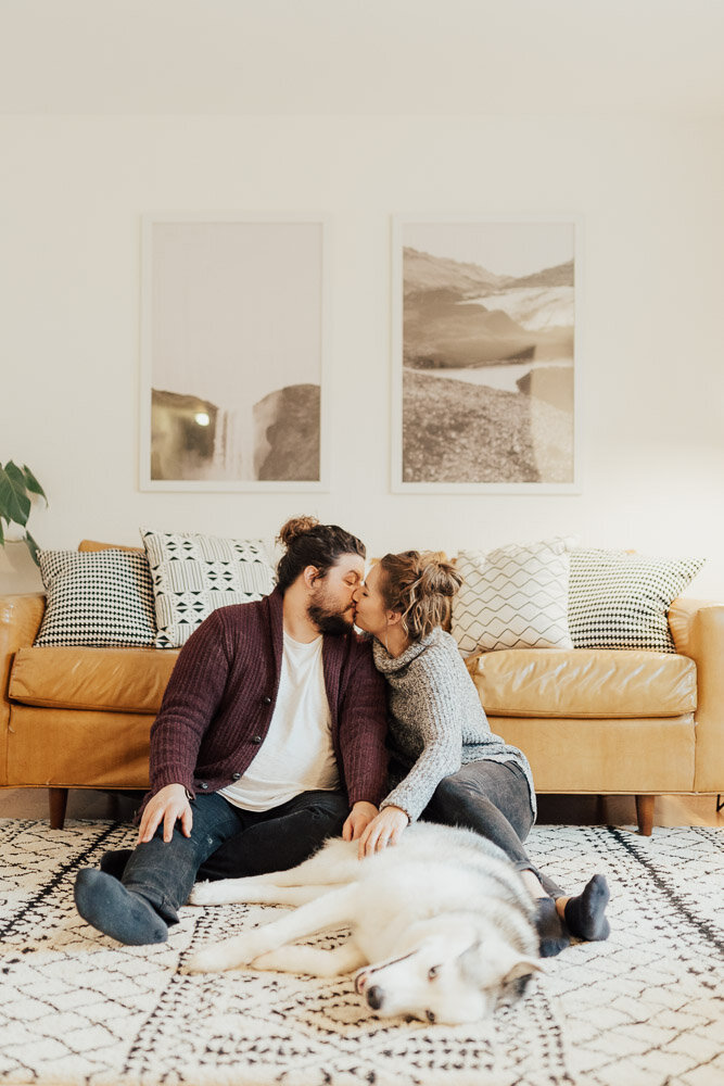 couple kissing in home photoshoot with husky
