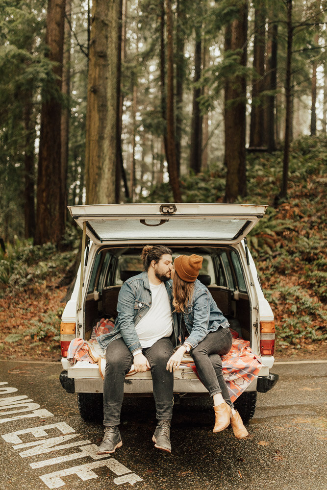 couple kissing back of jeep in washington forest engagement photoshoot