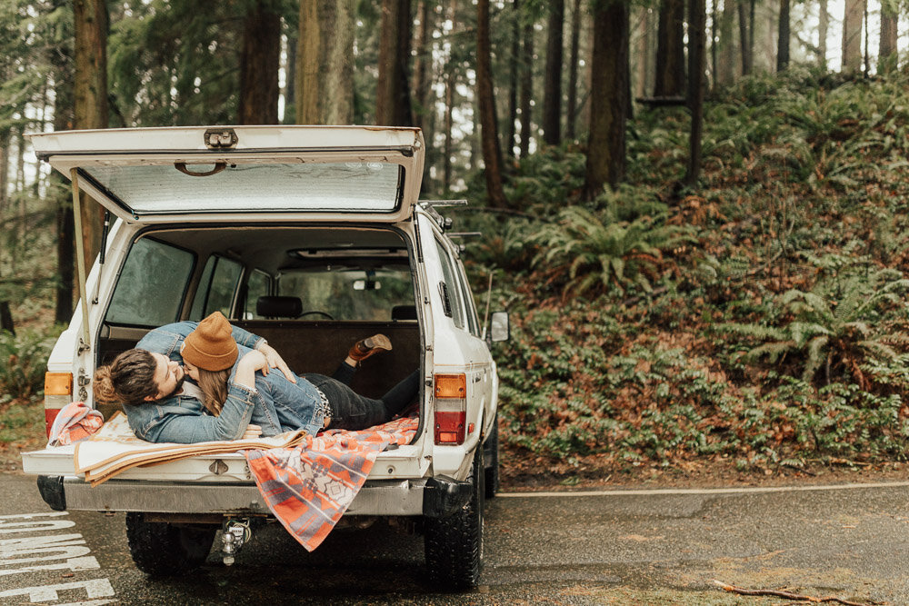Couple laughing and snuggling in back of jeep washington forest engagement photoshoot