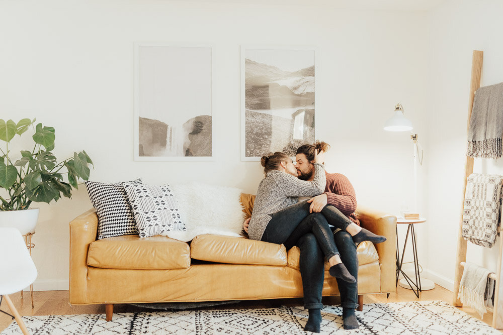 couple kissing on couch in home engagement photoshoot